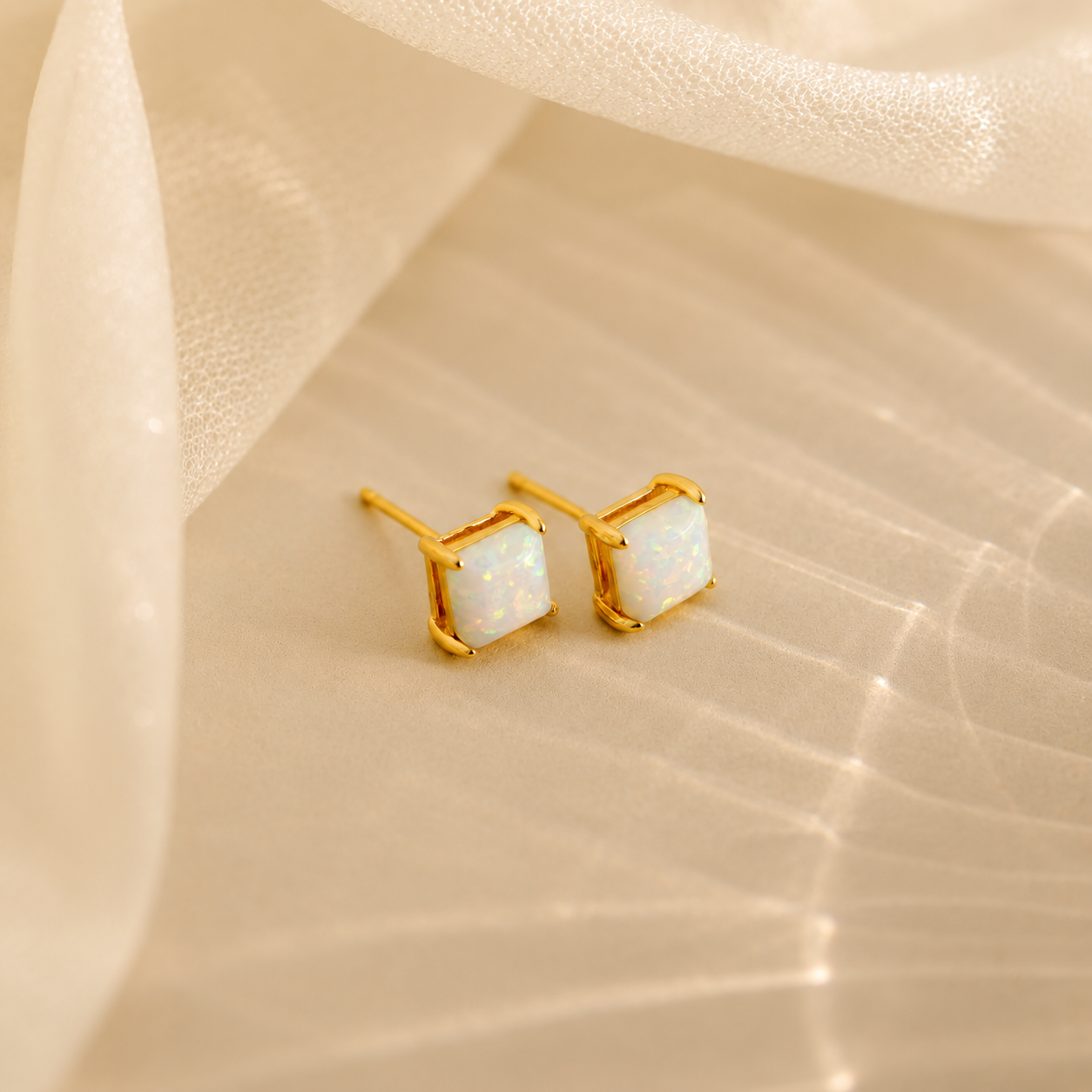 Gold earrings with white gemstones on a beige fabric background